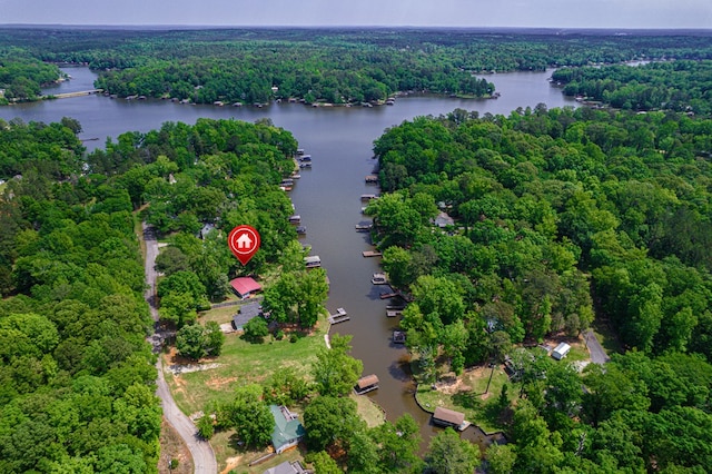 aerial view of property and surrounding area with a heavily wooded area and a large body of water