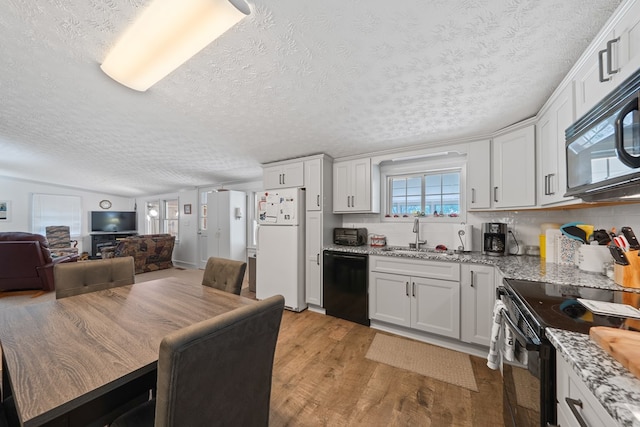 kitchen with black appliances, a sink, light wood finished floors, a textured ceiling, and backsplash