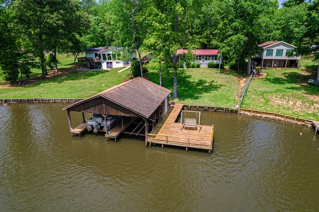 dock with boat lift, a water view, and a lawn