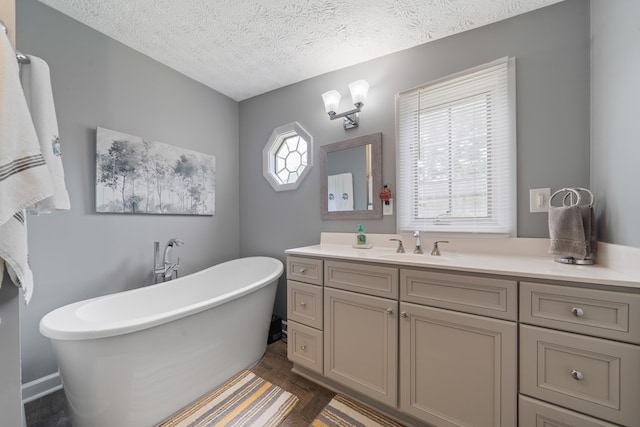 bathroom featuring vanity, a freestanding tub, a textured ceiling, and wood finished floors
