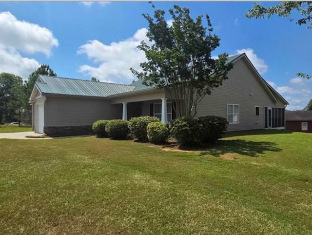 179 Garrett Dr, Eatonton, GA 31024 - view of property exterior featuring an attached garage, a yard, a metal roof, and driveway
