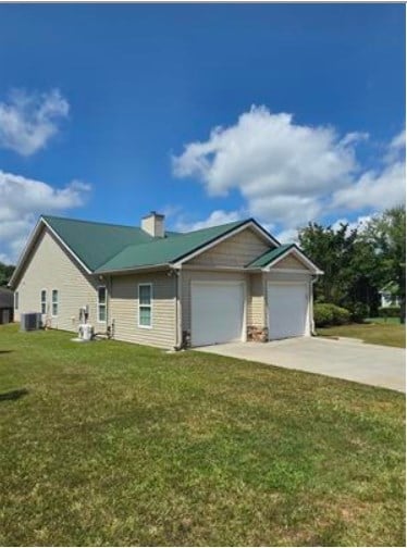 179 Garrett Dr, Eatonton, GA 31024 - view of front facade with an attached garage, driveway, a front yard, and a chimney