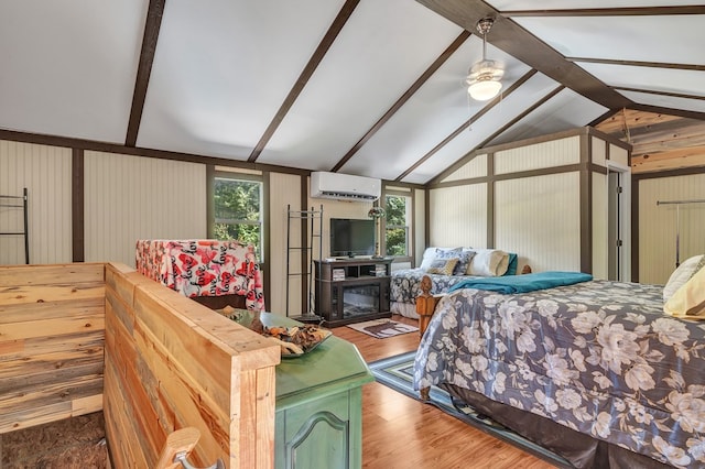 bedroom featuring vaulted ceiling with beams, an AC wall unit, a glass covered fireplace, and wood finished floors