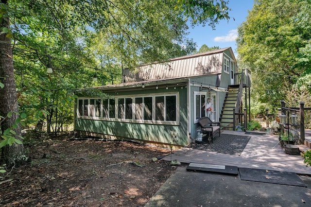 exterior space with a sunroom, stairs, and a gambrel roof