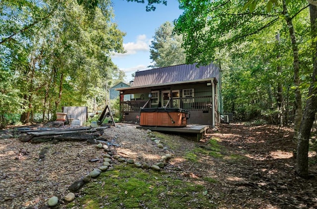 rear view of property featuring a deck, metal roof, and a hot tub