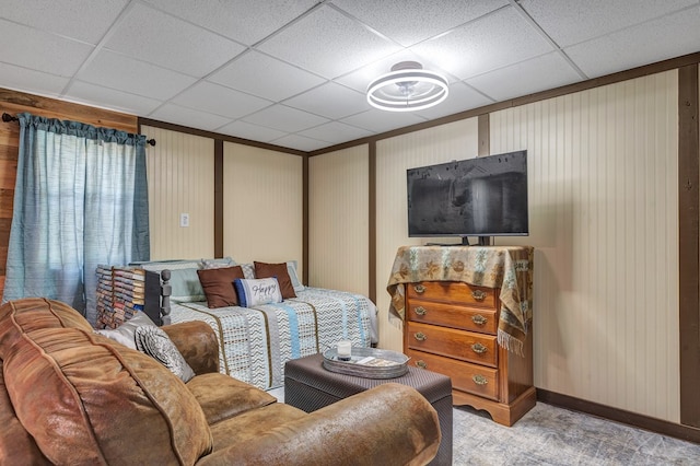 living area with carpet, a drop ceiling, and baseboards