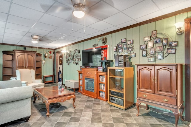 living room with crown molding, a paneled ceiling, and ceiling fan