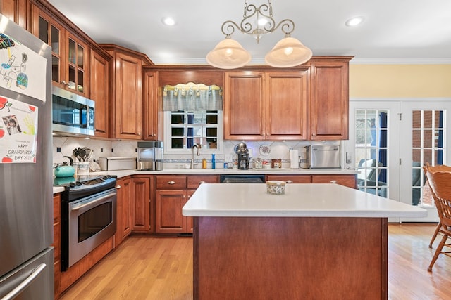 kitchen with stainless steel appliances, light countertops, ornamental molding, glass insert cabinets, and pendant lighting