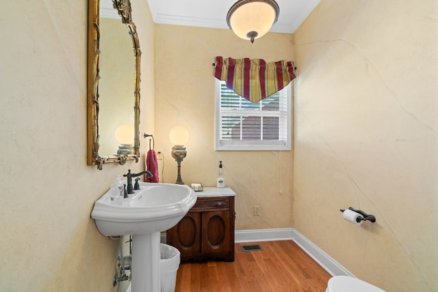 bathroom featuring baseboards, crown molding, visible vents, and wood finished floors