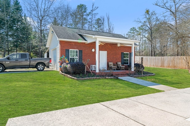 view of front of home with a porch, a garage, brick siding, fence, and a front yard