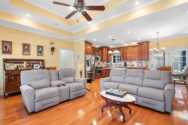 living room featuring crown molding, recessed lighting, a raised ceiling, and light wood-style floors