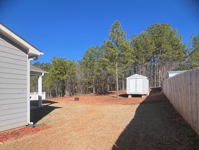 view of yard featuring a fenced backyard, a storage unit, and an outdoor structure