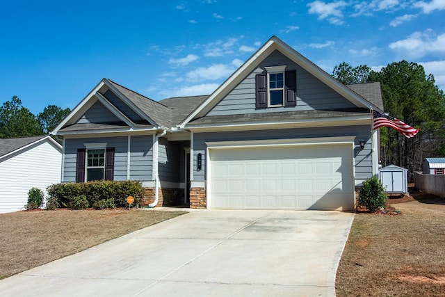 view of front of house featuring stone siding, a storage unit, a garage, and driveway