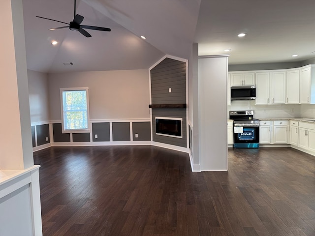 unfurnished living room with a fireplace, vaulted ceiling, ceiling fan, and dark wood-type flooring