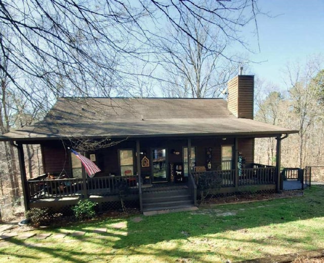 rear view of house featuring a porch, a lawn, and a chimney