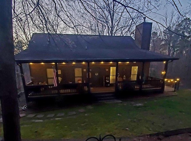 back of property featuring covered porch and a chimney