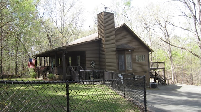 102 Treanor Dr, Milledgeville, GA 31061 - view of home's exterior with a chimney, stairway, aphalt driveway, a fenced front yard, and a lawn