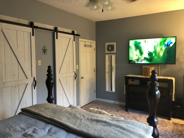 102 Treanor Dr, Milledgeville, GA 31061 - bedroom featuring baseboards, a barn door, and a textured ceiling