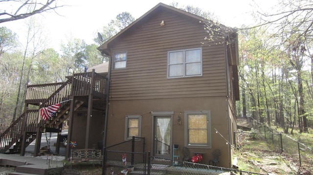 102 Treanor Dr, Milledgeville, GA 31061 - rear view of house featuring stucco siding, a fenced front yard, stairway, and a deck