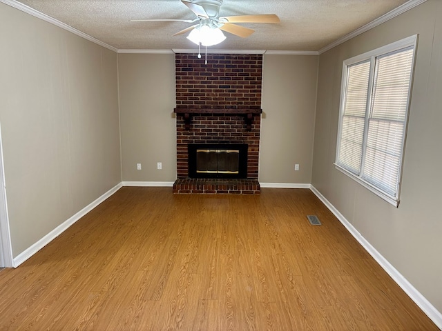 unfurnished living room with a textured ceiling, crown molding, a fireplace, wood finished floors, and a ceiling fan