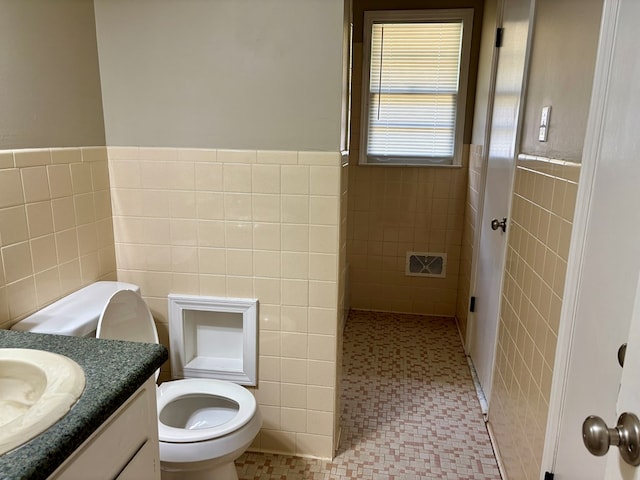 full bathroom with tile patterned floors, vanity, and tile walls