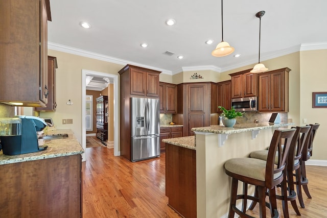 128A Montego Bay Rd, Milledgeville, GA 31061 - kitchen featuring appliances with stainless steel finishes, a breakfast bar area, light wood-style floors, baseboards, and backsplash