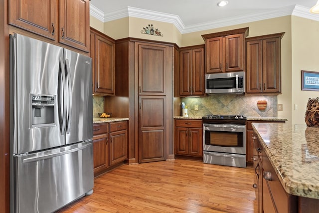 128A Montego Bay Rd, Milledgeville, GA 31061 - kitchen with appliances with stainless steel finishes, light wood-style floors, ornamental molding, light stone counters, and decorative backsplash