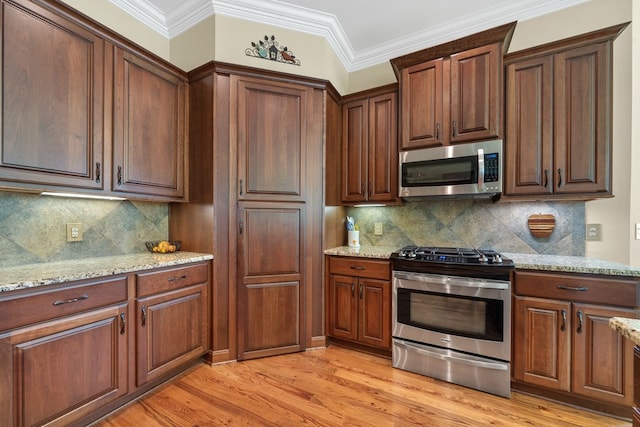 128A Montego Bay Rd, Milledgeville, GA 31061 - kitchen featuring stainless steel appliances, light stone counters, light wood-style floors, backsplash, and ornamental molding