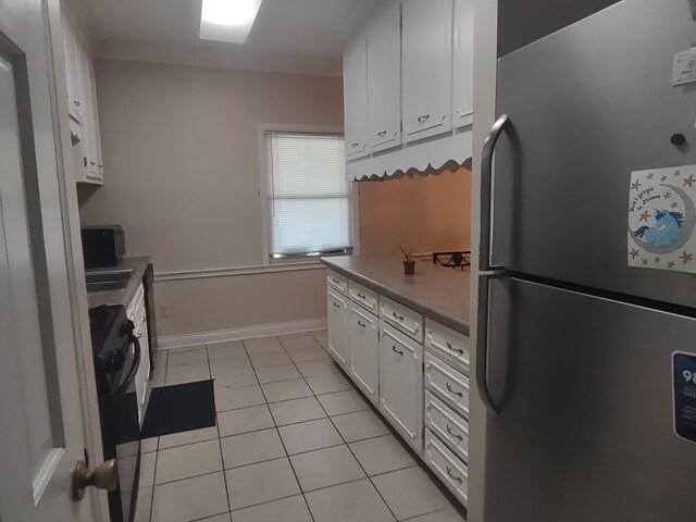 1745 Cedarwood Dr, Milledgeville, GA 31061 - kitchen featuring freestanding refrigerator, white cabinets, light tile patterned floors, and baseboards