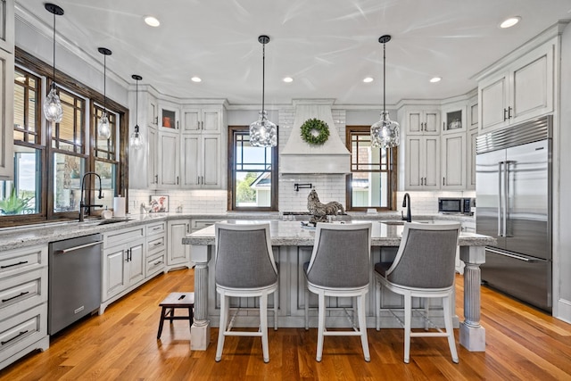 kitchen featuring light hardwood / wood-style flooring, a kitchen island, hanging light fixtures, and appliances with stainless steel finishes