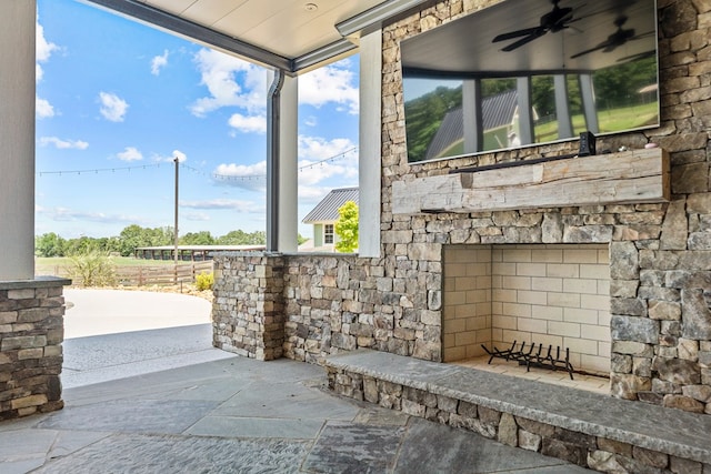 view of patio / terrace with ceiling fan and an outdoor stone fireplace