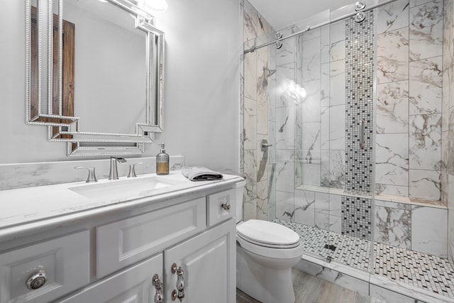 bathroom with tiled shower, vanity, hardwood / wood-style flooring, and toilet