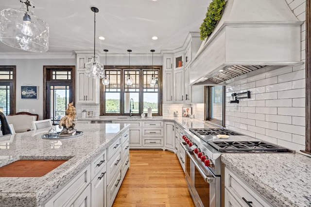 kitchen with white cabinetry, stainless steel stove, and hanging light fixtures