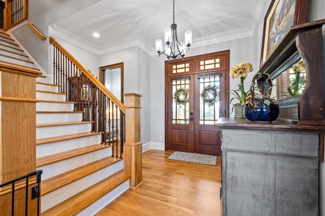 entrance foyer featuring french doors, an inviting chandelier, light hardwood / wood-style floors, and ornamental molding