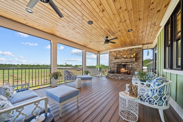 wooden terrace with an outdoor stone fireplace and ceiling fan