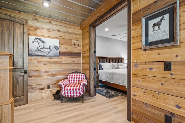 bedroom featuring wood walls and light hardwood / wood-style flooring