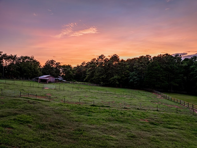 yard at dusk with a rural view and an outdoor structure