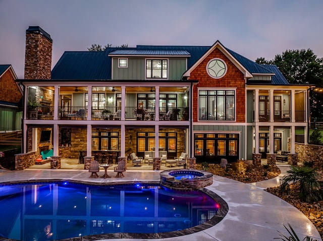 back house at dusk with a pool with hot tub and a patio area