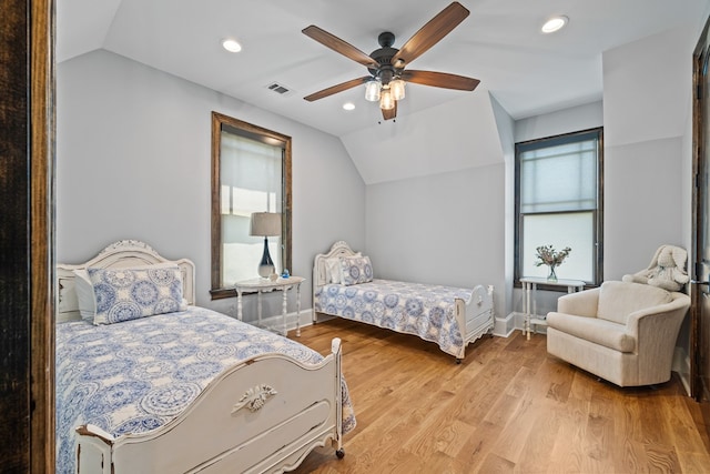 bedroom with ceiling fan, light hardwood / wood-style floors, and vaulted ceiling