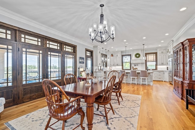 dining area featuring light wood-type flooring, french doors, crown molding, and an inviting chandelier