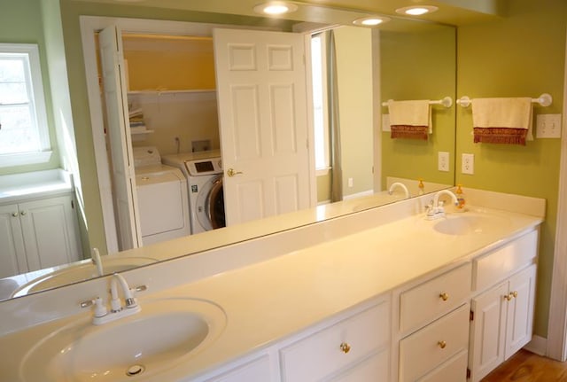 full bathroom with double vanity, washing machine and dryer, and a sink