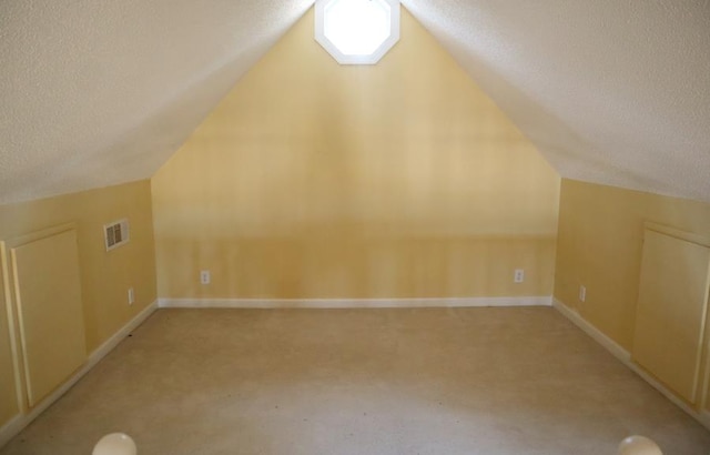 additional living space featuring lofted ceiling, visible vents, and a textured ceiling