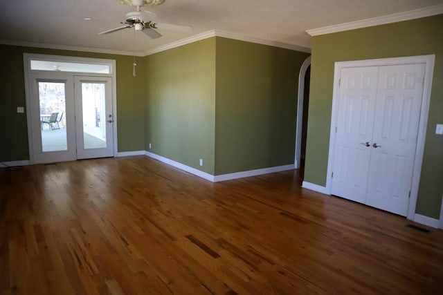 unfurnished room featuring arched walkways, dark wood finished floors, and crown molding