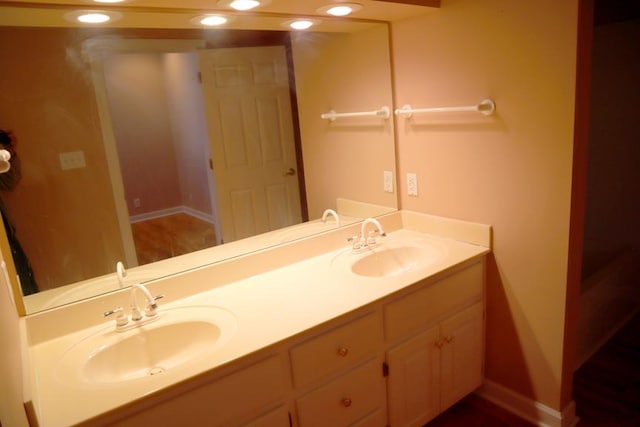 full bathroom featuring double vanity, baseboards, a sink, and recessed lighting