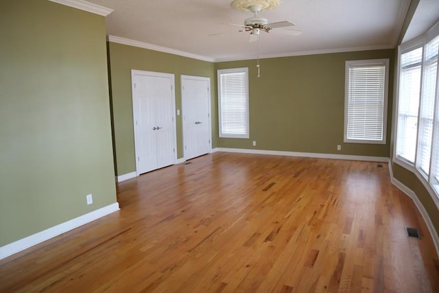 unfurnished bedroom featuring multiple windows, light wood-type flooring, and crown molding