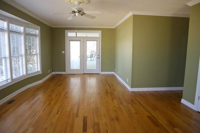 empty room with light wood finished floors, baseboards, ornamental molding, and ceiling fan