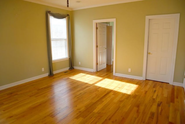 unfurnished bedroom with ornamental molding, light wood-style flooring, and baseboards