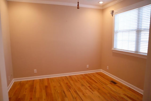 unfurnished room featuring baseboards, wood finished floors, visible vents, and crown molding