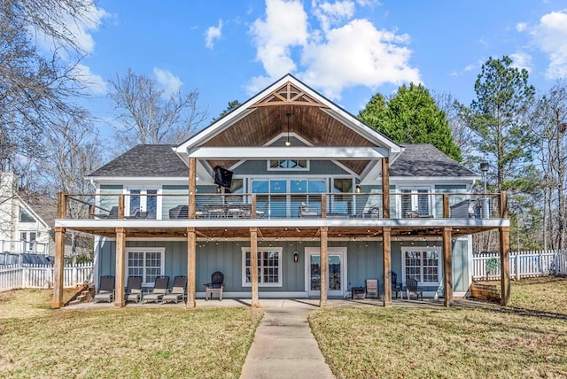 back of property with roof with shingles, a lawn, a patio area, fence, and a deck