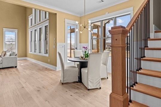 dining space with a notable chandelier, ornamental molding, and light hardwood / wood-style floors